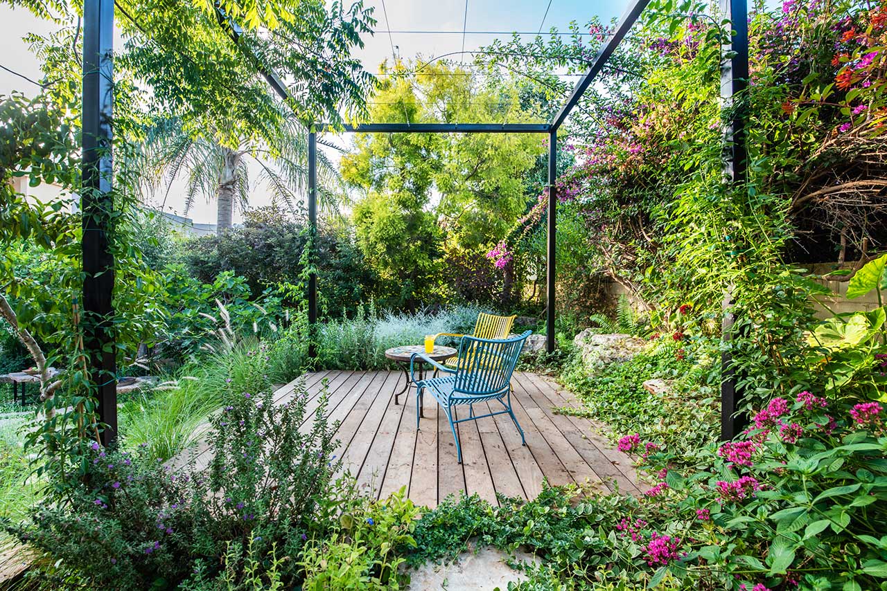 חלל מיוחד בלב הגינה בתל מונד המיועד לפינת ישיבה ומלא בצמחייה צבעונית